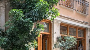 A building with a wooden door and windows, a balcony with metal railings, and a signboard. - Avli Lounge Apartments (Rethymno)