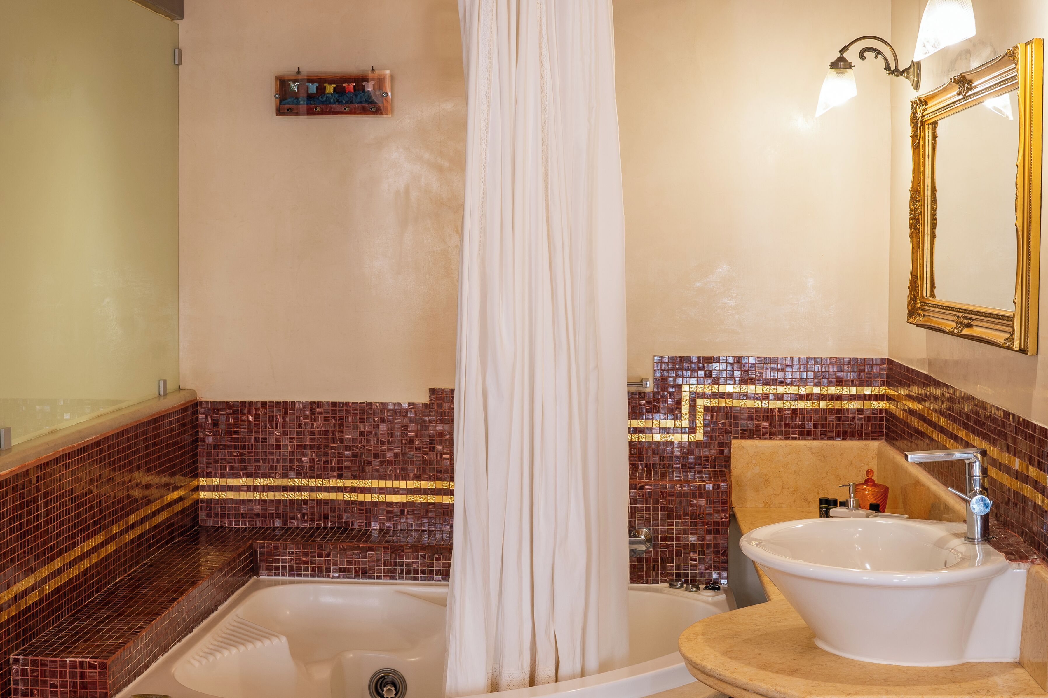 A bathroom with a bathtub, a sink, a mirror, and mosaic tile walls.