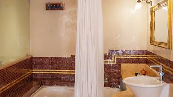 A bathroom with a bathtub, a sink, a mirror, and mosaic tile walls.
