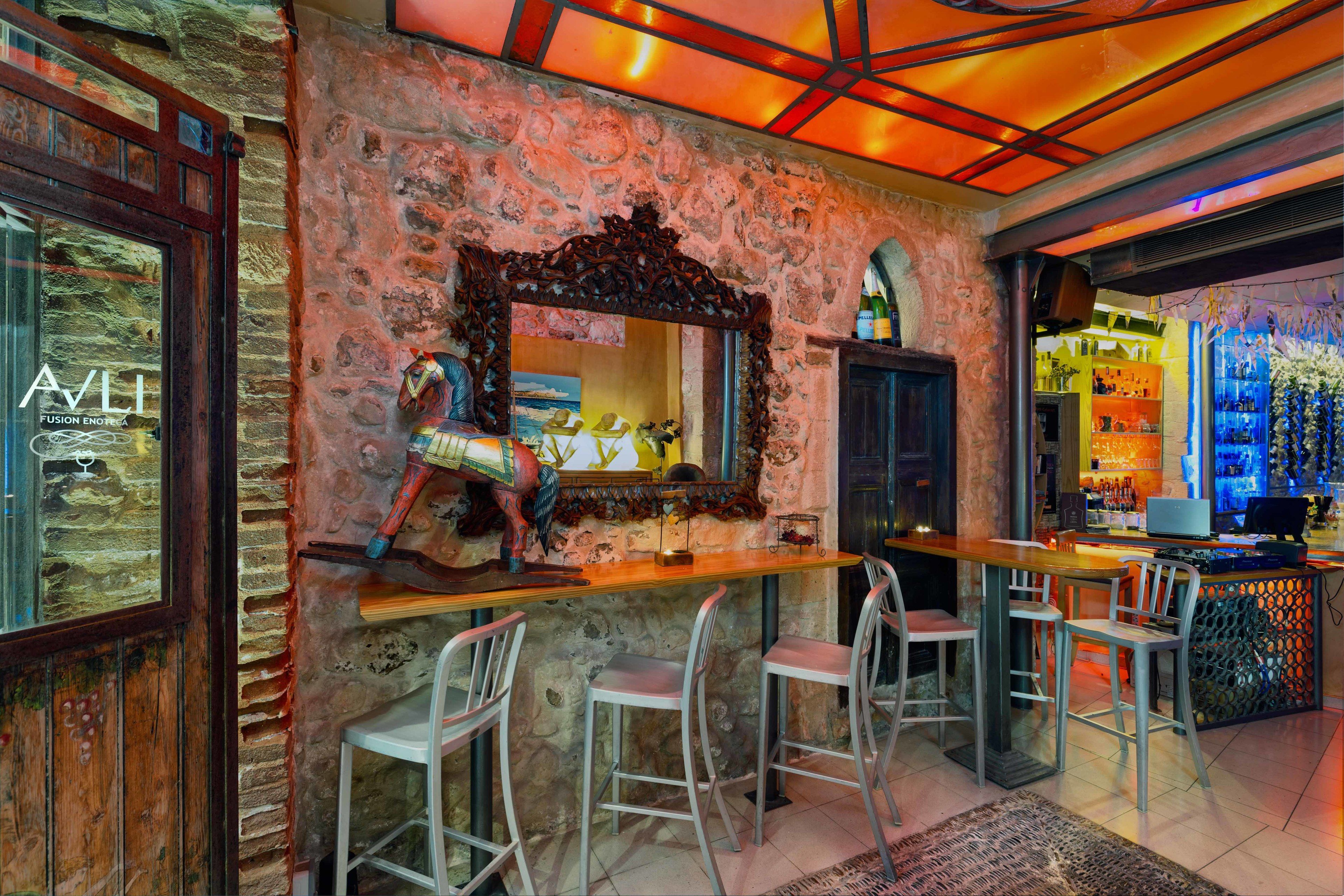 A bar area with stone walls, a wooden counter, and metal bar stools.