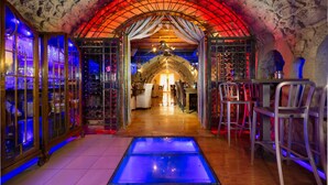 An interior with a stone archway, a central glass floor, and wooden furniture. - Avli Lounge Apartments (Rethymno)