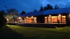 A modern house with a covered porch, large windows, and a well-lit exterior at dusk.