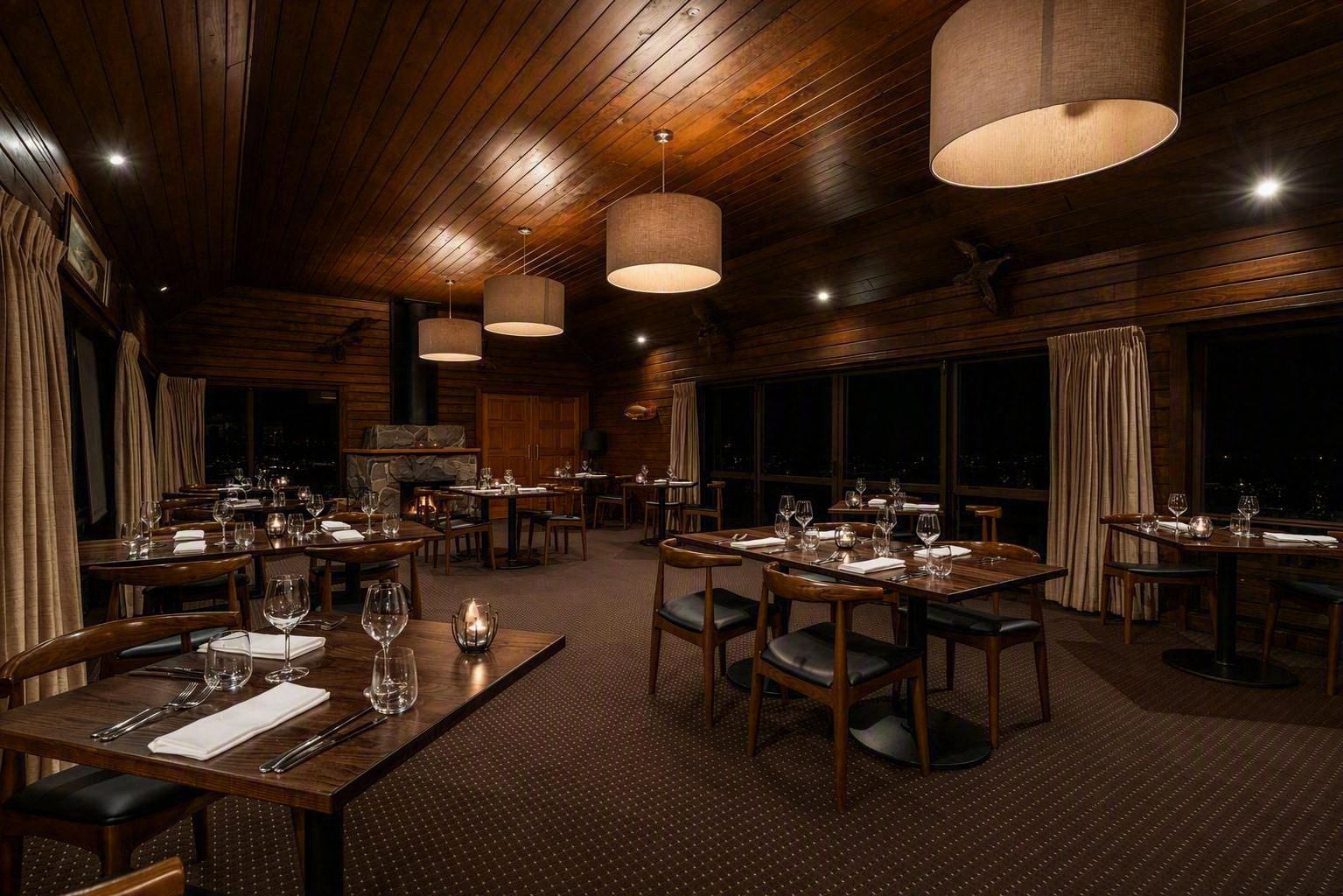 A restaurant with wooden interiors, multiple dining tables, and hanging pendant lights.