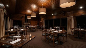 Un restaurante con interiores de madera, varias mesas de comedor y lámparas colgantes.