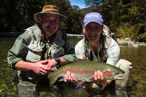 Two people holding a large fish in clear water.