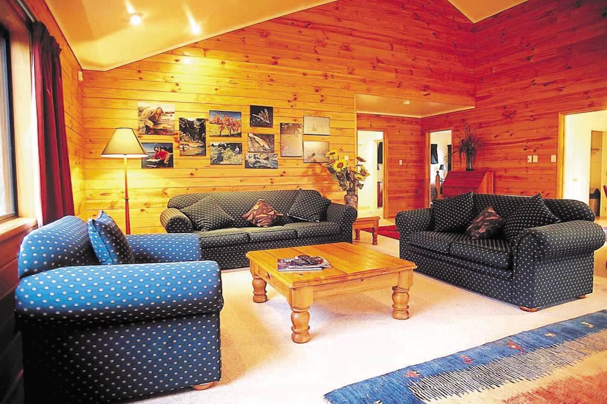 A cozy log cabin interior with a living room featuring two sofas, a coffee table, and a rug.