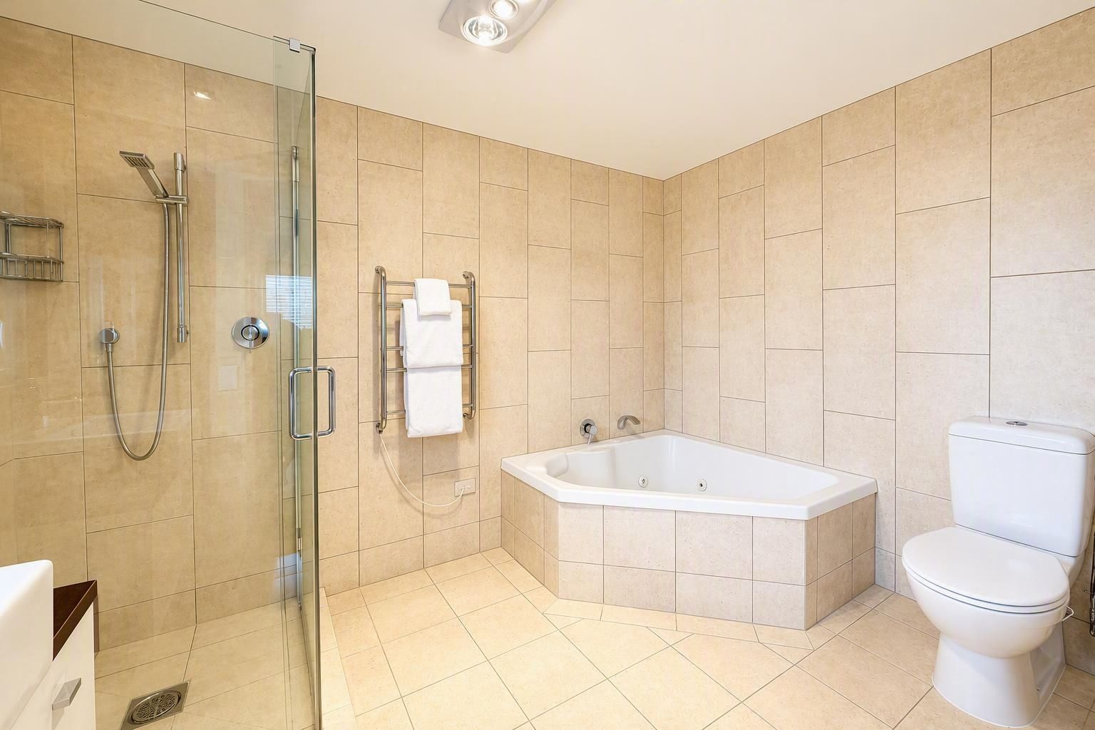 A modern bathroom with a glass-enclosed shower, a freestanding bathtub, and a toilet.