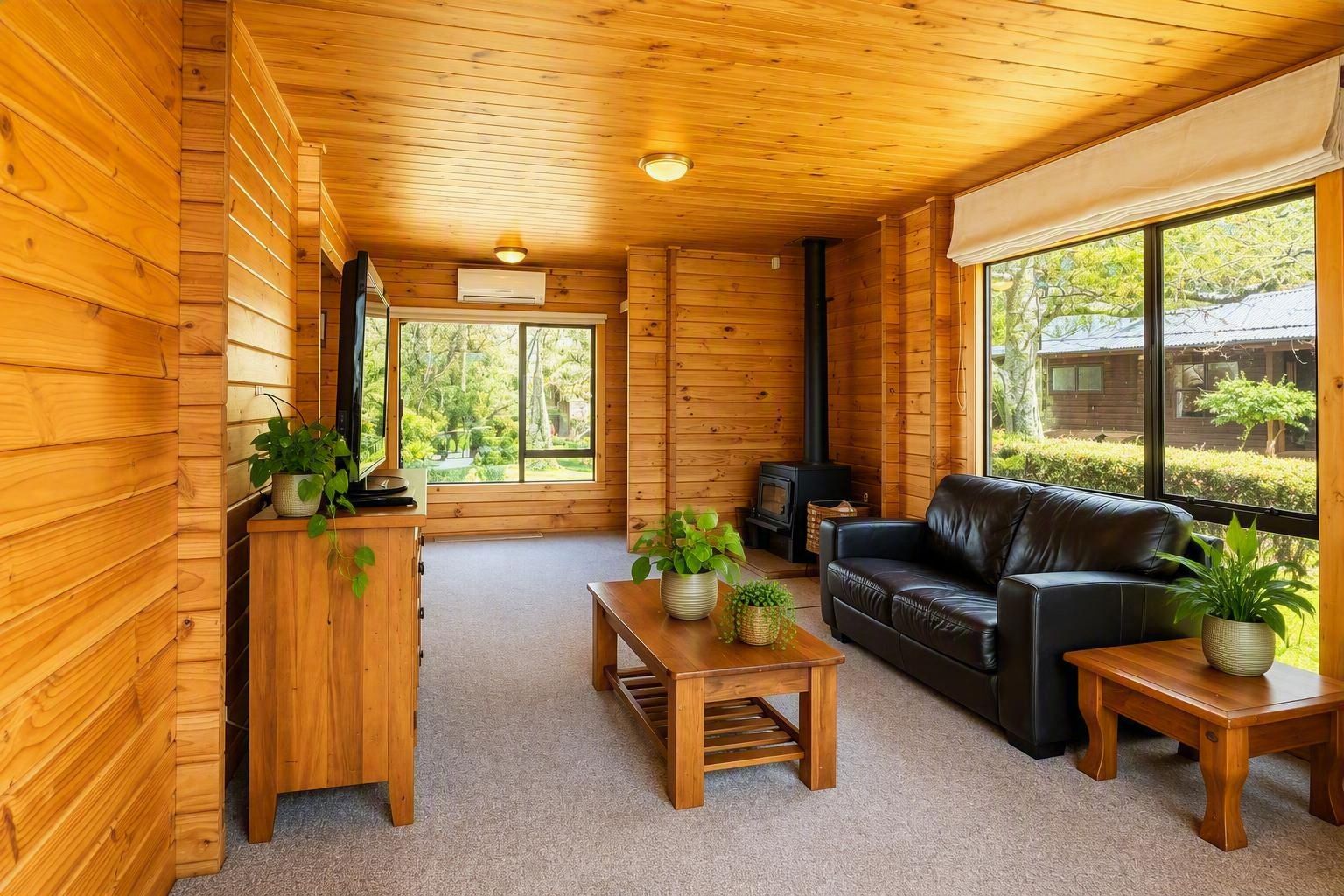 A cozy cabin interior with wooden walls, a fireplace, a sofa, and a television.