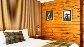 Una habitación con una cama, una mesita de noche, una lámpara y dos cuadros en la pared.