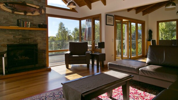 Un salón amplio con chimenea, suelo de madera y un ventanal que ofrece vistas al exterior.