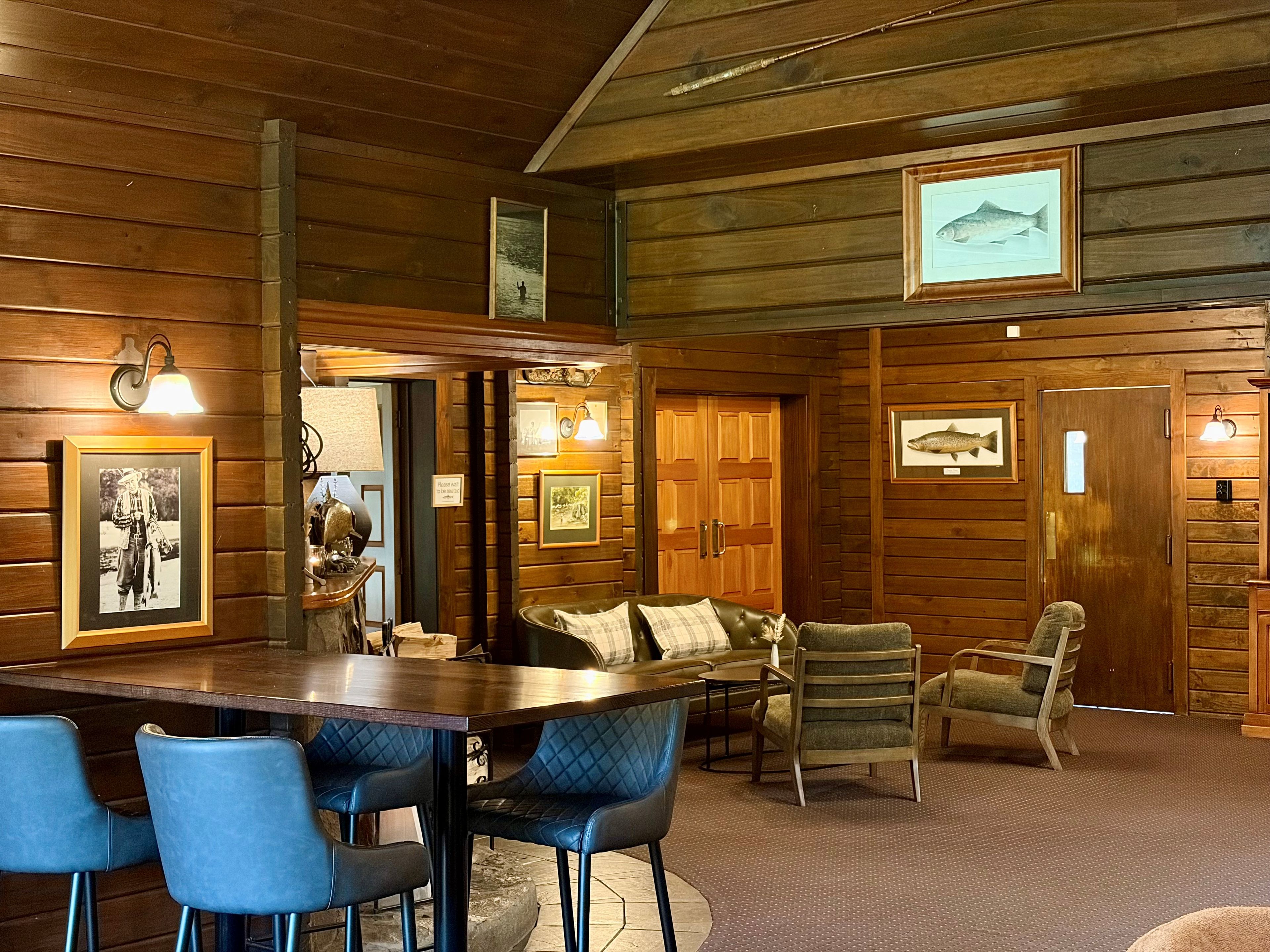 A wooden interior with a bar area, seating, and framed pictures on the walls.