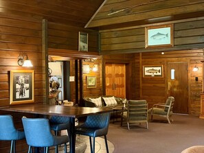 A wooden interior with a bar area, seating, and framed pictures on the walls.