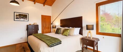 Un dormitorio con cama, mesita de noche, lámpara y ventana con persianas.