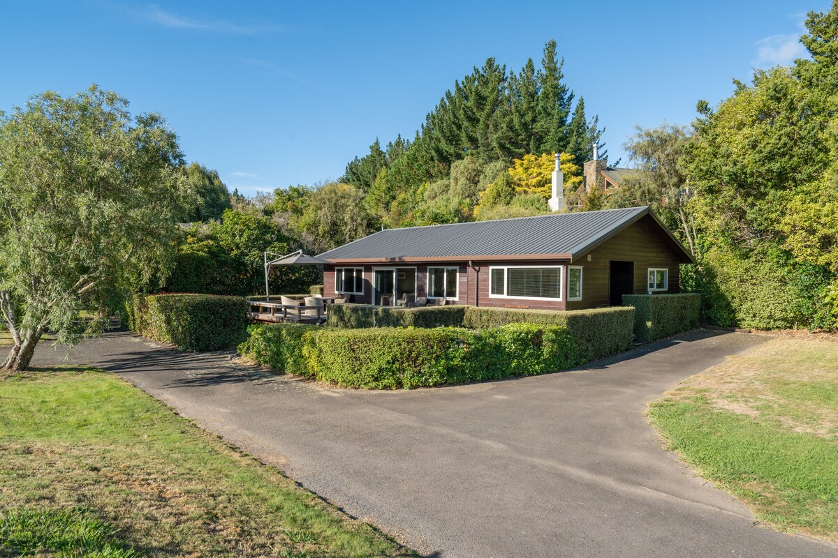 A single-story house with a sloped roof, a covered porch, and a paved driveway.