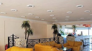Un vestíbulo con sofás amarillos, una pared de piedra y una escalera.