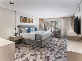 Habitación de hotel moderna con una cama grande, un escritorio, una silla, un televisor y vistas al exterior.