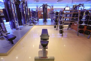 A gym with various exercise equipment, including weight machines, benches, and a rack of dumbbells.