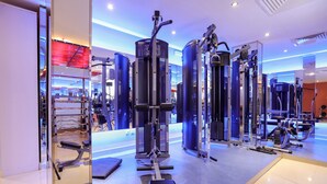 Un gimnasio moderno con diversas máquinas de ejercicio, una banca y un muro con espejos.