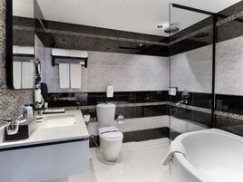 Un baño moderno con ducha envuelta en vidrio, una bañera blanca y un inodoro.