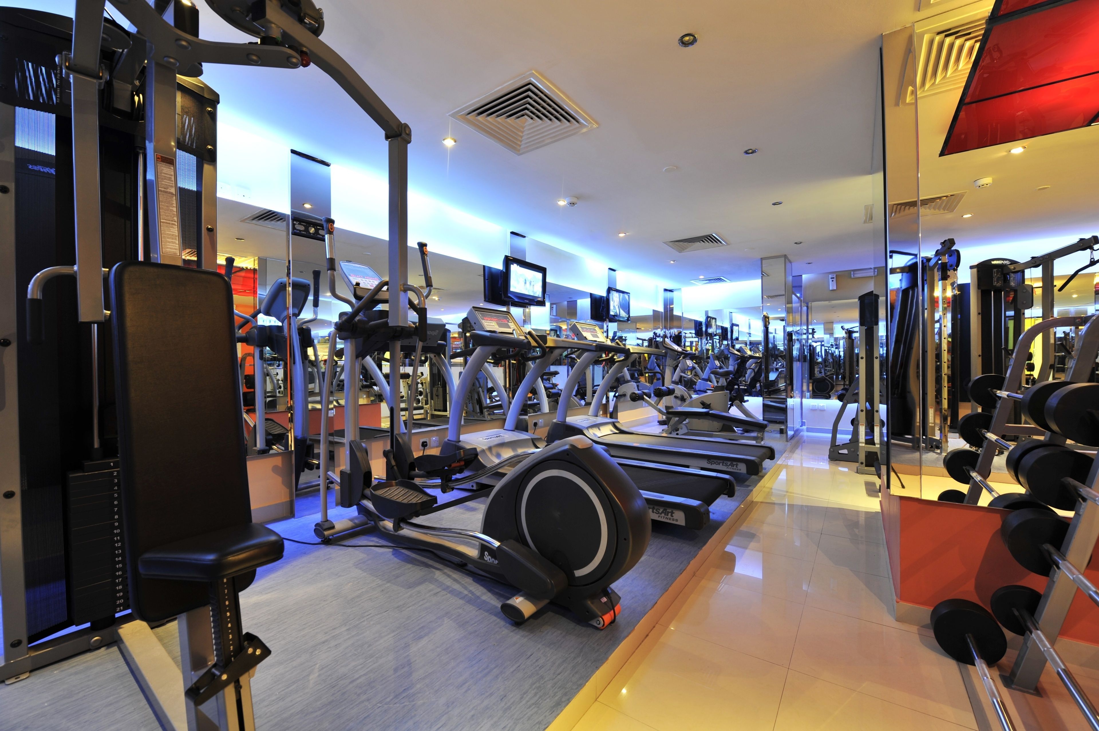 A gym with various exercise equipment, including treadmills, ellipticals, and weight machines.