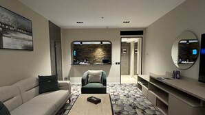 Una sala de estar moderna con sofá, sillón, mesa de centro y televisión.