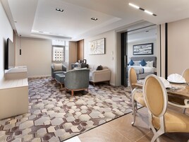 A modern hotel room with a dining area, a sofa set, and a patterned floor.