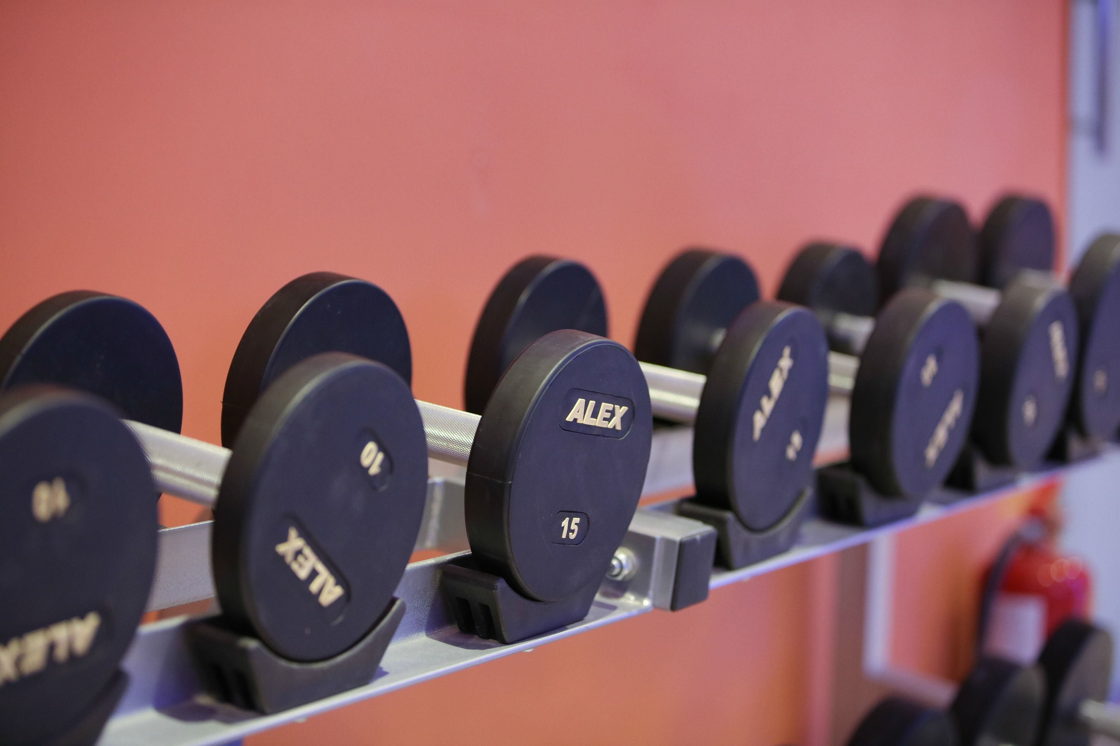 A rack of dumbbells with labels, including "ALEX" and weight numbers.