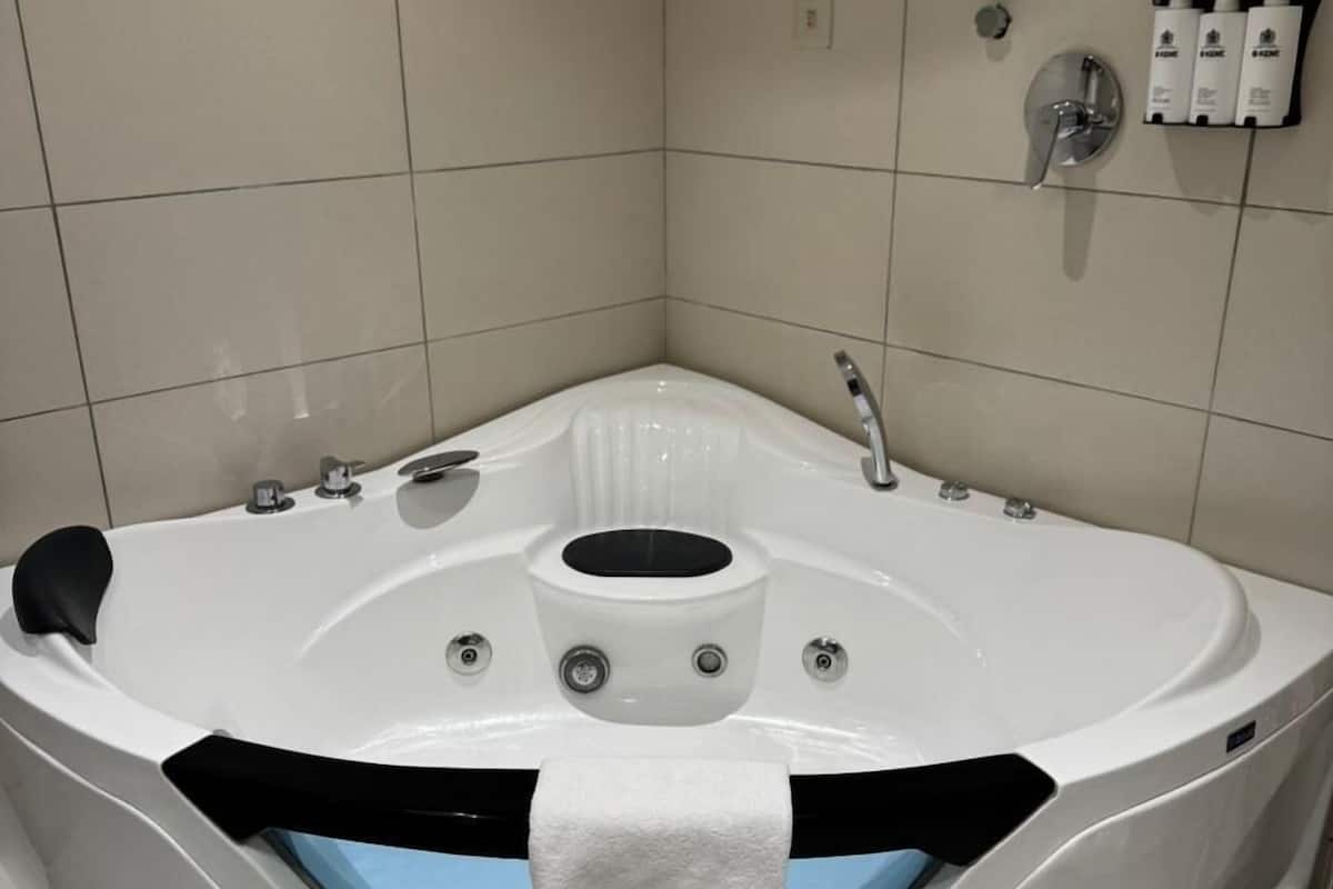 A modern bathroom with a large, curved bathtub, a built-in showerhead, and a towel rack.