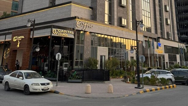 Un hotel con un cartel llamativo que dice "Continent Hotel Al Wahda" y una "Capital Lounge" en la planta baja.