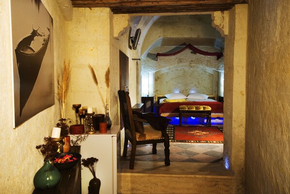 A narrow hallway leading to a bedroom with a bed, a chair, and a table with candles.