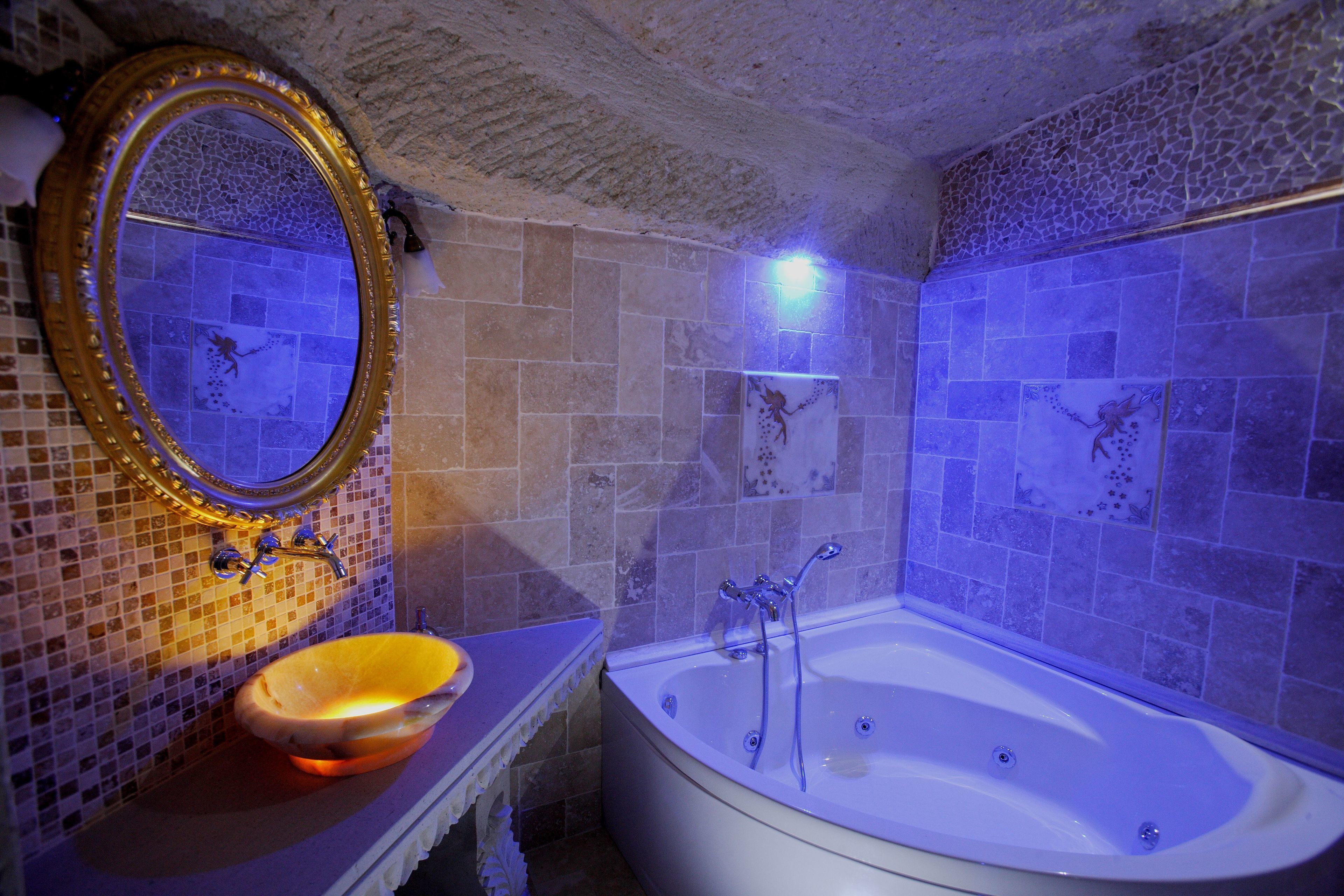 A bathroom with a bathtub, a sink with a bowl, and a mirror with a gold frame.