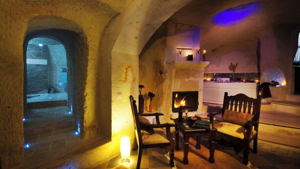 A cozy interior with stone walls, a fireplace, and seating. - Perimasali Cave Hotel - Cappadocia (Ürgüp)