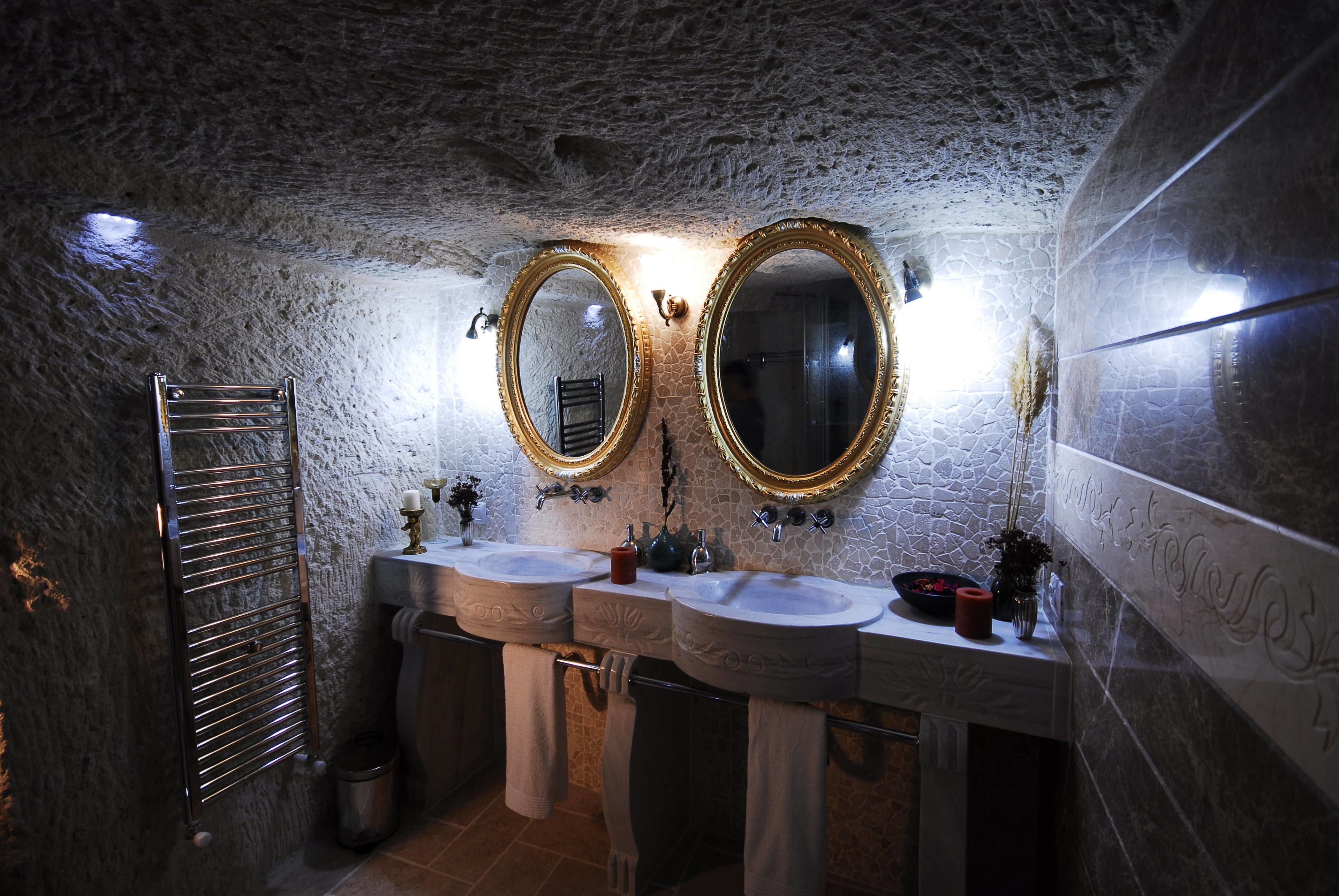 A bathroom with two sinks, two mirrors, a towel rack, and a trash can.