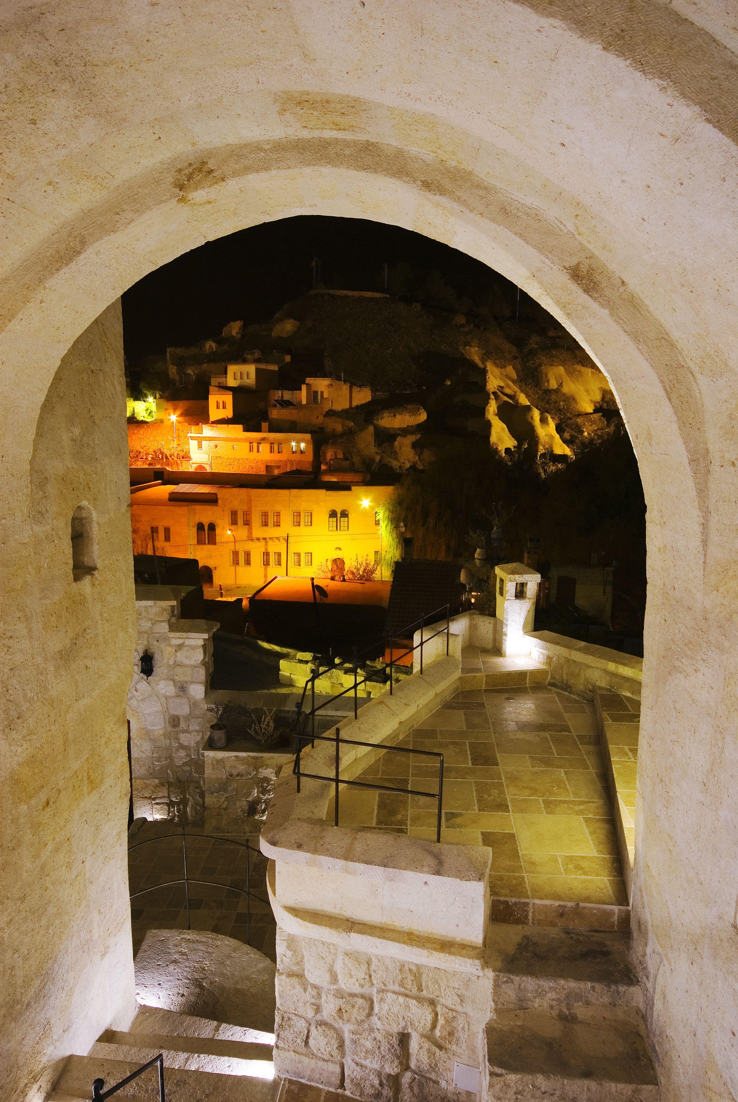 A stone staircase leading to a higher level, with a view of a building illuminated by warm lights.