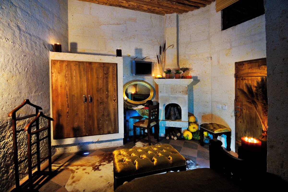 A rustic room with a wooden wardrobe, a television, a fireplace, and a mirror.