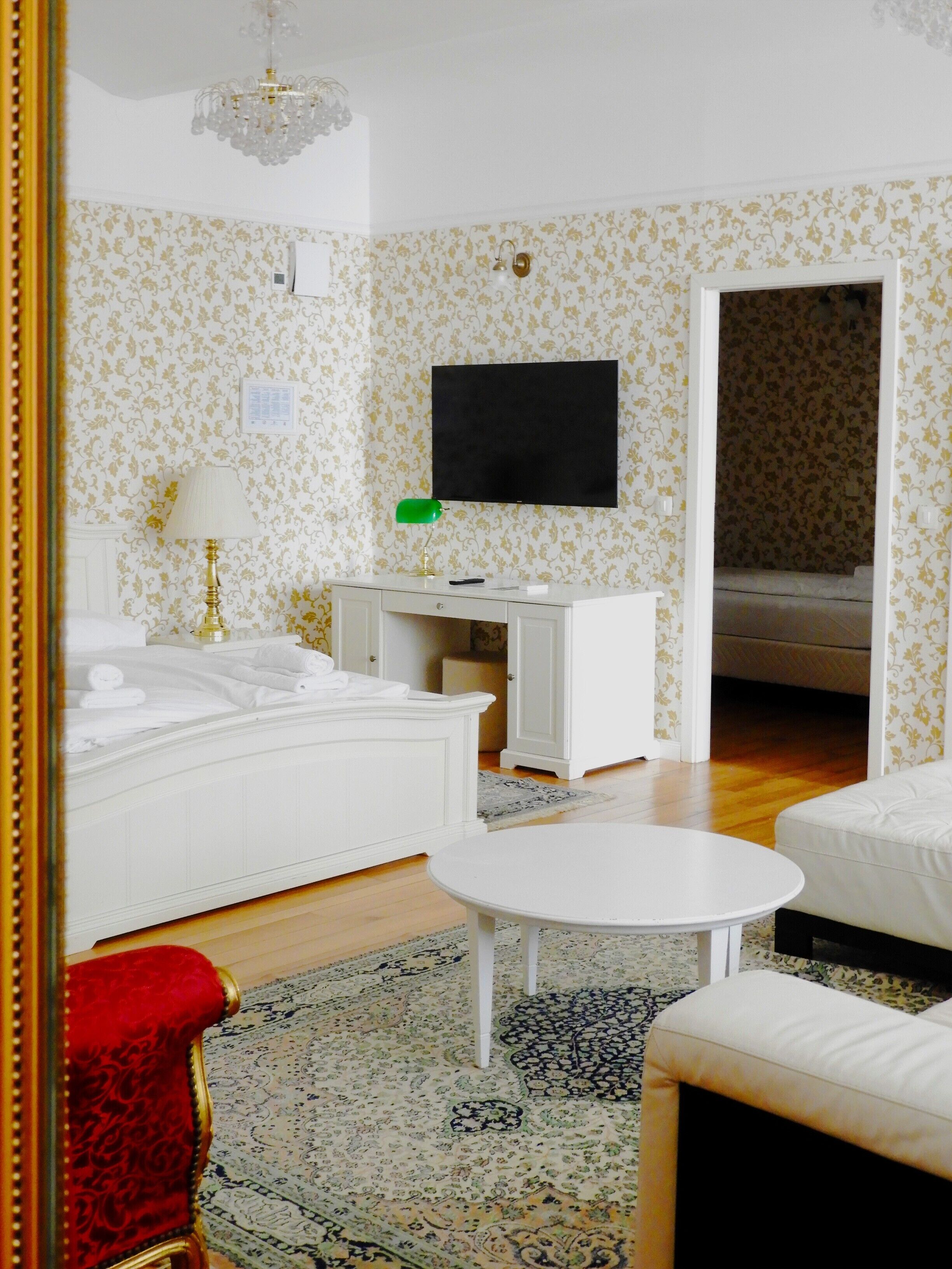 A hotel room with a bed, a desk, a television, and a red armchair.