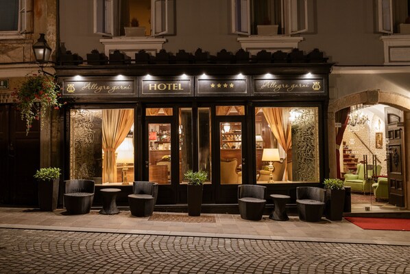 A hotel facade with a classic design, featuring a signboard, multiple windows, and outdoor seating. - Allegro Hotel (Ljubljana)