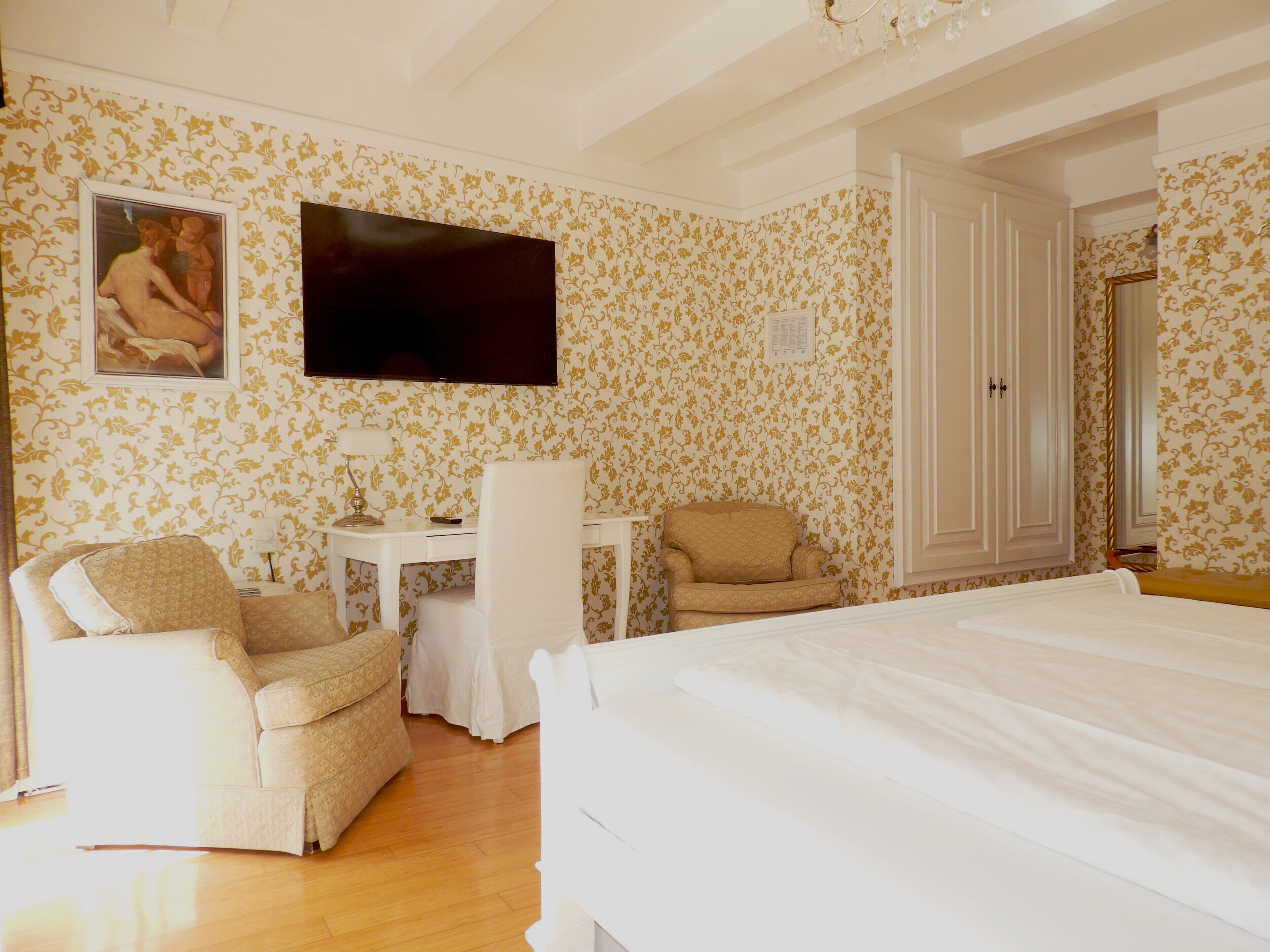 A hotel room with a bed, a desk, a chair, a television, and a wardrobe.