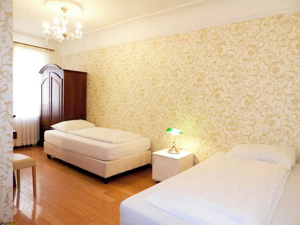 A bedroom with a bed, a nightstand, a dresser, and a chandelier.