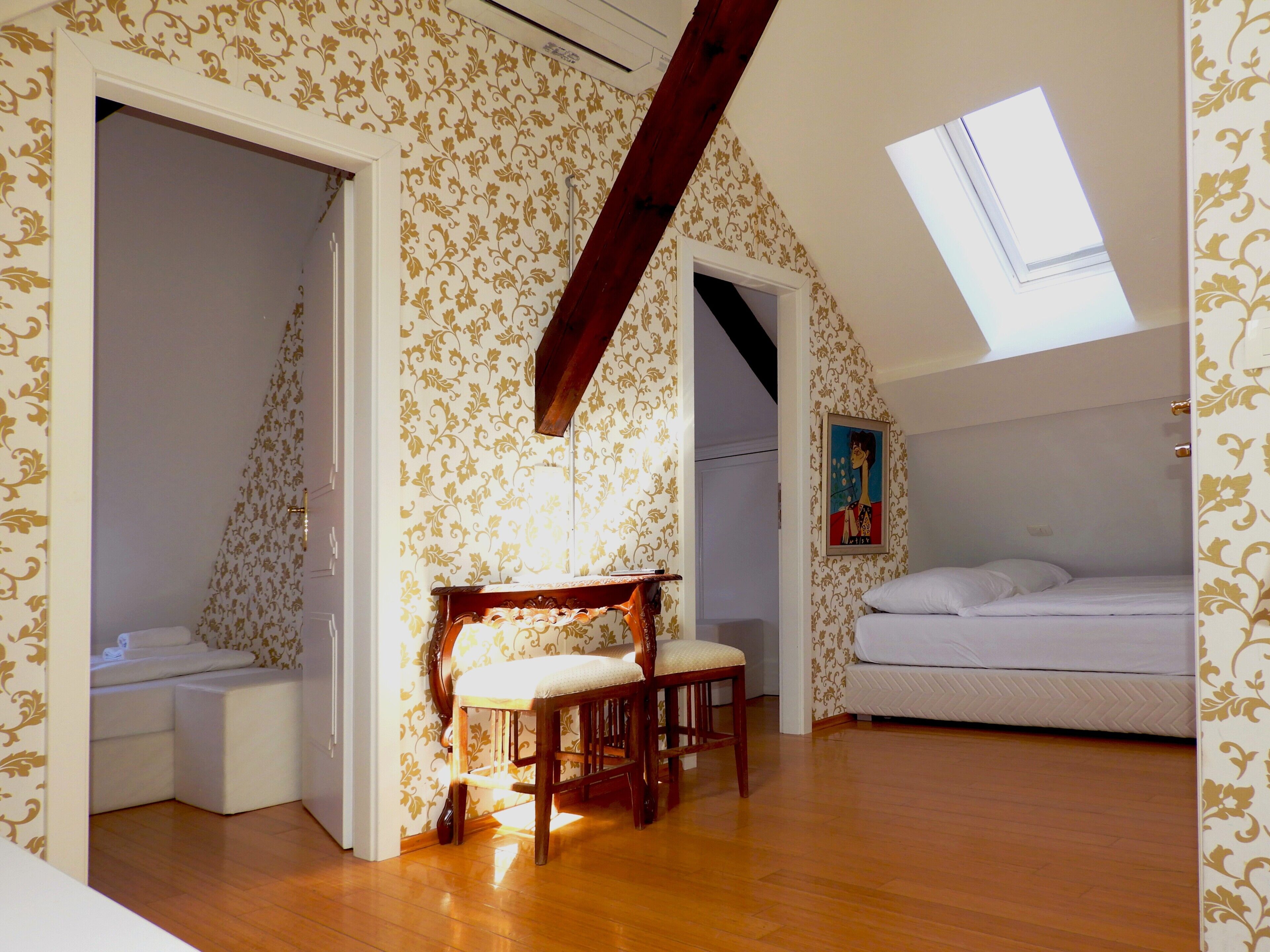 A bedroom with a bunk bed, a wooden bench, and a skylight.