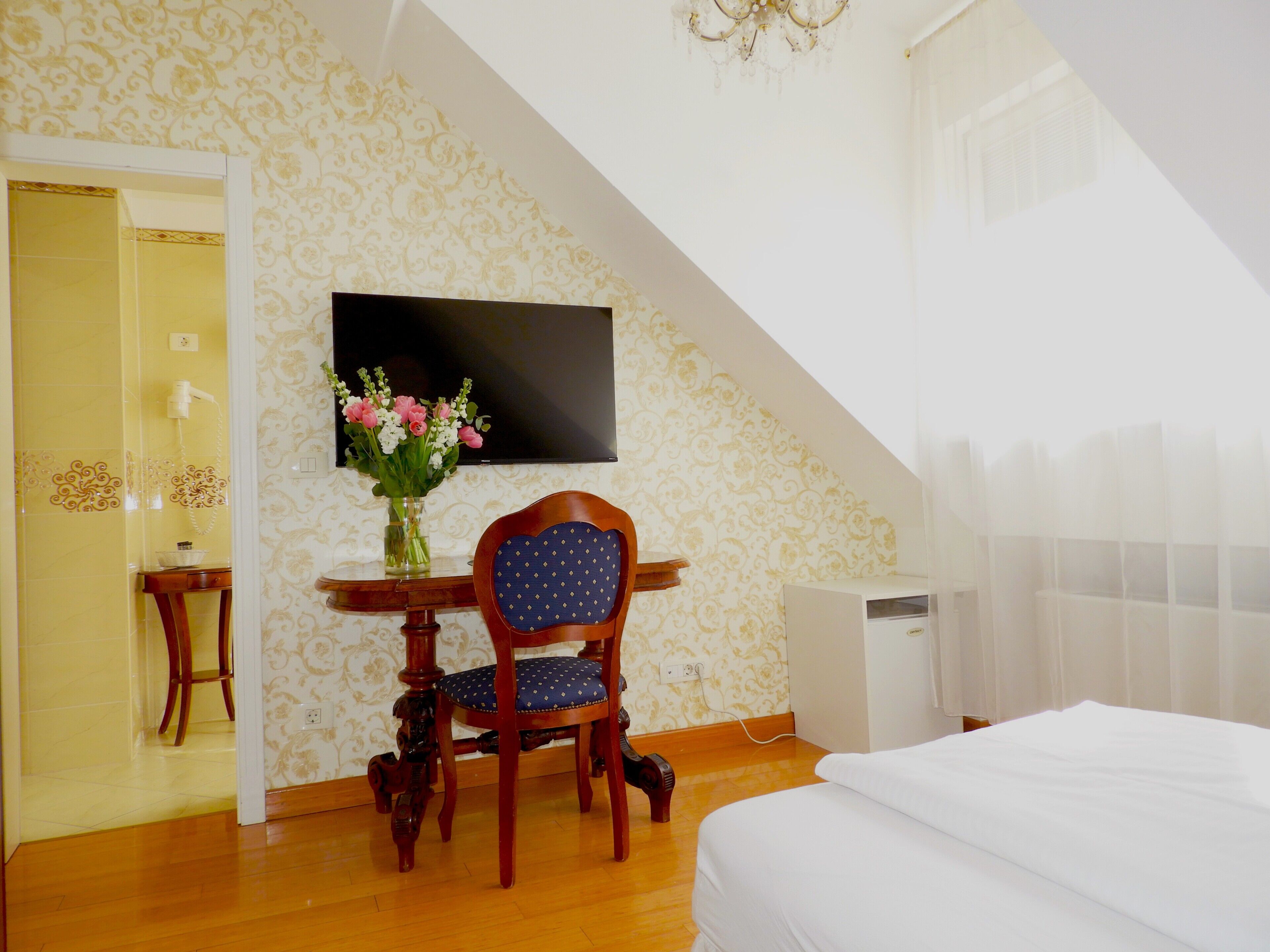 Un dormitorio con cama, un escritorio con silla, televisor y zona de ducha.