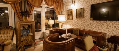 A traditional living room with a sofa, armchairs, a wooden coffee table, a television, and a decorative cabinet.