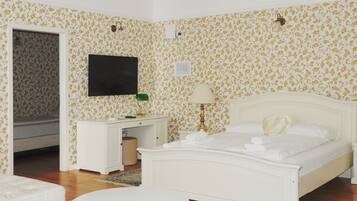 A bedroom with a bed, a desk, a chair, a TV, and a chandelier.