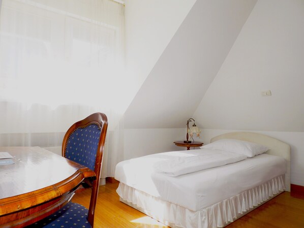 A room with a bed, a chair, a table, and a lamp.