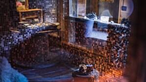 A mosaic-tiled room with a wooden bench and a small table.