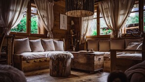 A rustic wooden room with a sofa, a wooden chest, and a hanging light fixture.