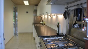 Una cocina moderna con electrodomésticos de acero inoxidable, una estufa a gas y ollas colgantes.