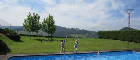 Una piscina al aire libre, sombrillas, sillones reclinables de piscina