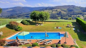 Una piscina con sillas de descanso, vistas a colinas onduladas y un césped bien cuidado.