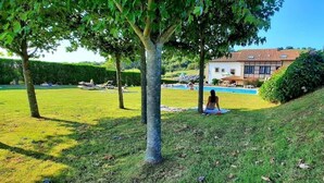 Un espacio con césped, una piscina, una casa y árboles.